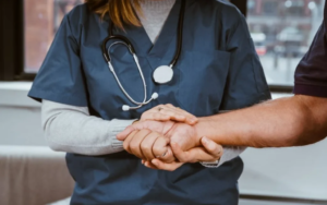 A female healthcare professional holding a man’s hand.