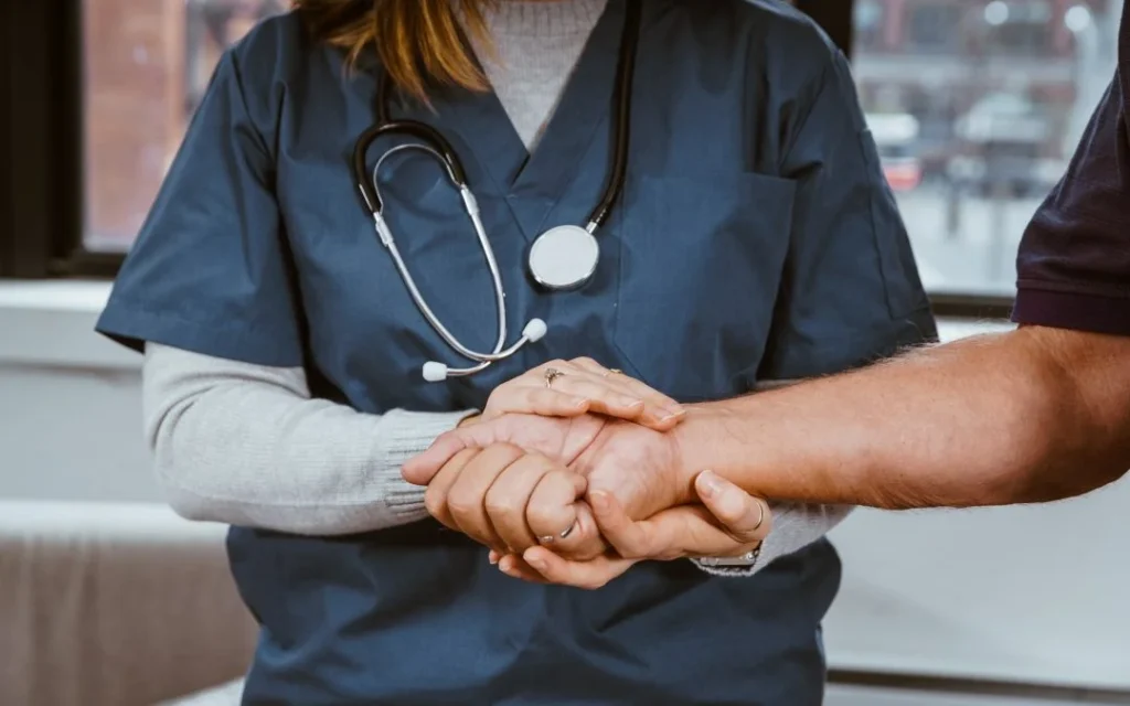 A female healthcare professional holding a man’s hand.
