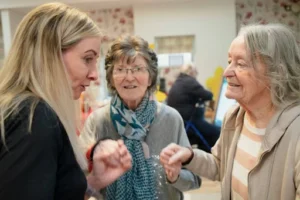 Woman assisting and having a conversation with two elderly women