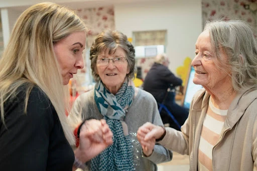 Woman assisting and having a conversation with two elderly women