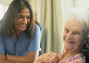 A caregiver and an elderly person smiling