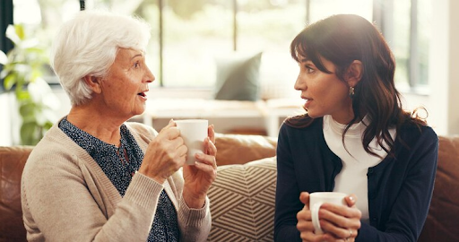 An elderly woman talking to a mature woman