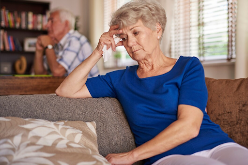 An elderly woman looking distressed on a sofa