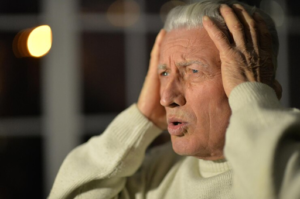 Distressed elderly man holding his head
