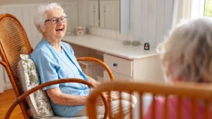 Older woman smiling while talking with another senior in an assisted living home